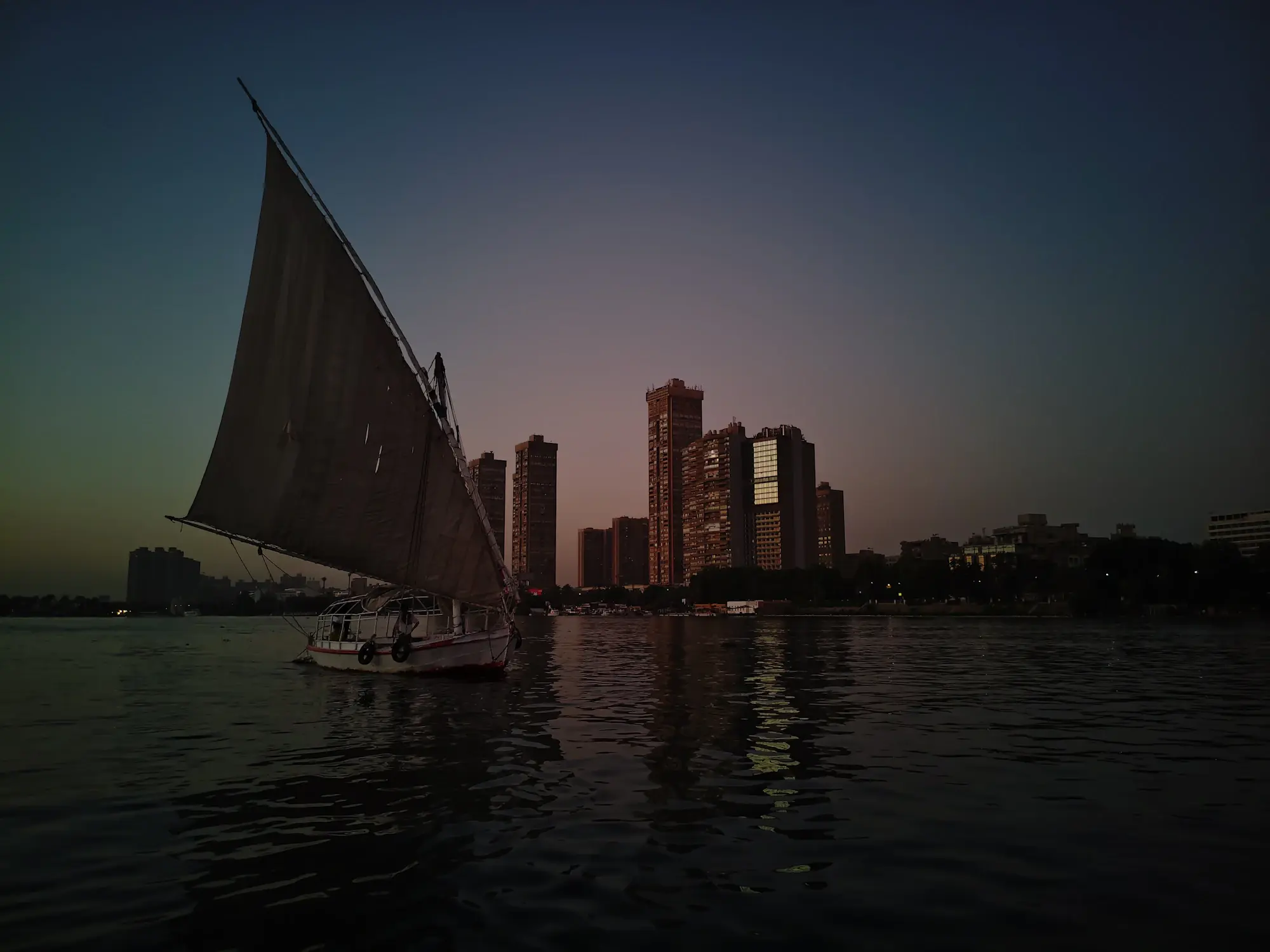 Felucca sailing on the Nile at dusk with the Cairo skyline behind